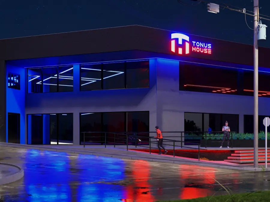 Fachada da Tonus House à noite, com luz azul e o logo vermelho aceso